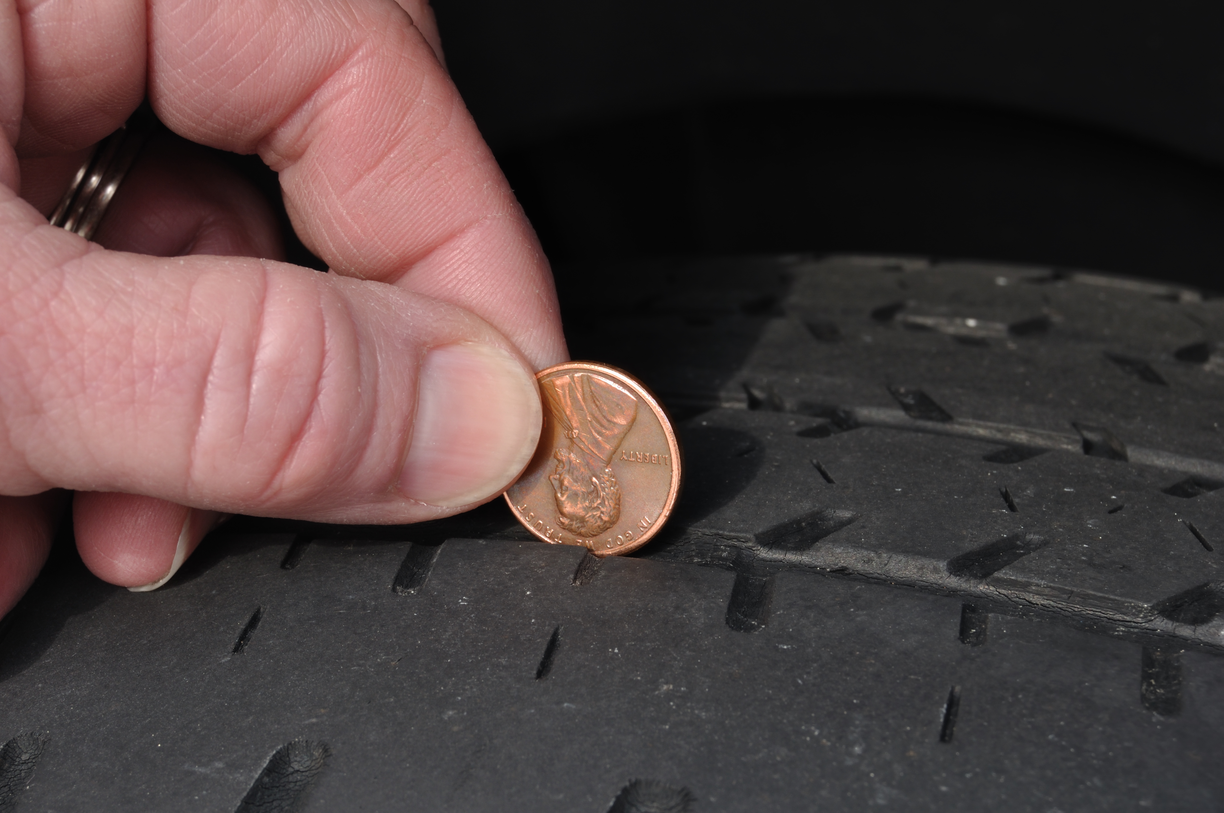 a mechanic checking the tread on a tire with a penny